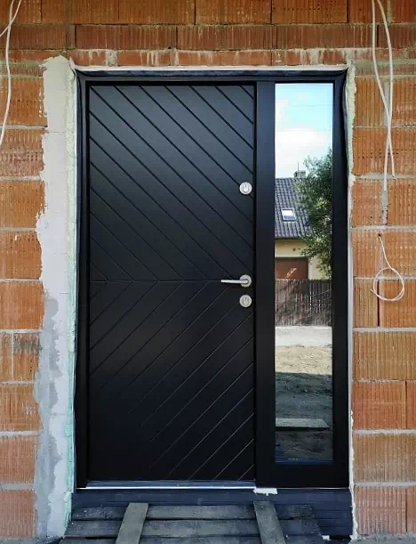 Widok elewacji domu z zamontowanymi drzwiami wzór 542,2 wymalowanymi w kolorze czarne.