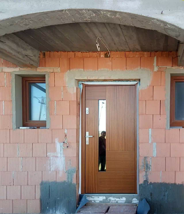 Widok elewacji domu z zamontowanymi drzwiami wzór 413,11C wymalowanymi w kolorze złoty dąb.