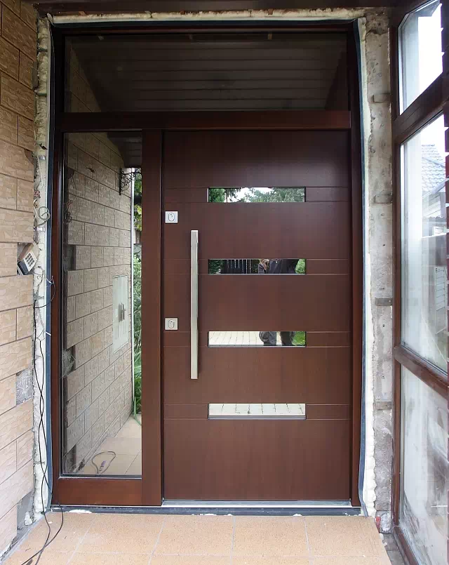 Widok elewacji domu z zamontowanymi drzwiami wzór 422,13 wymalowanymi w kolorze orzech.