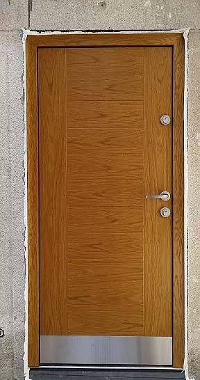 Widok elewacji domu z zamontowanymi drzwiami wzór 433,1 wymalowanymi w kolorze złoty dąb.