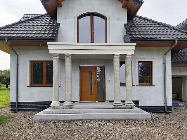 Widok elewacji domu z zamontowanymi drzwiami wzór 476,4+ds1 wymalowanymi w kolorze złoty dąb.