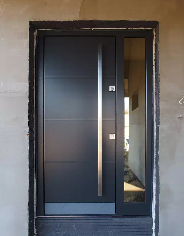 Widok elewacji domu z zamontowanymi drzwiami wzór 490,2 wymalowanymi w kolorze antracytowe.