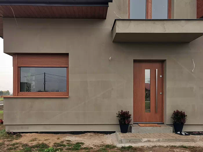 Widok elewacji domu z zamontowanymi drzwiami wzór 499,12 wymalowanymi w kolorze ciemny dąb.