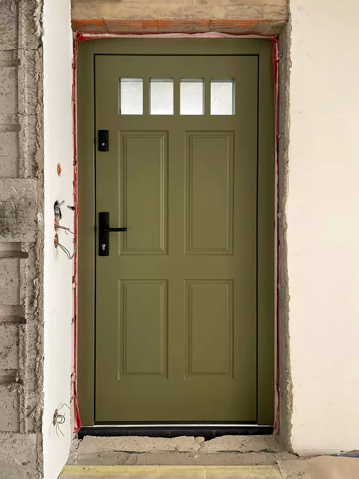 Widok elewacji domu z zamontowanymi drzwiami wzór 506,6 wymalowanymi w kolorze beżowe.