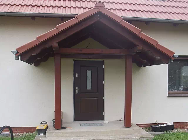 Widok elewacji domu z zamontowanymi drzwiami wzór 535,7 wymalowanymi w kolorze orzech.