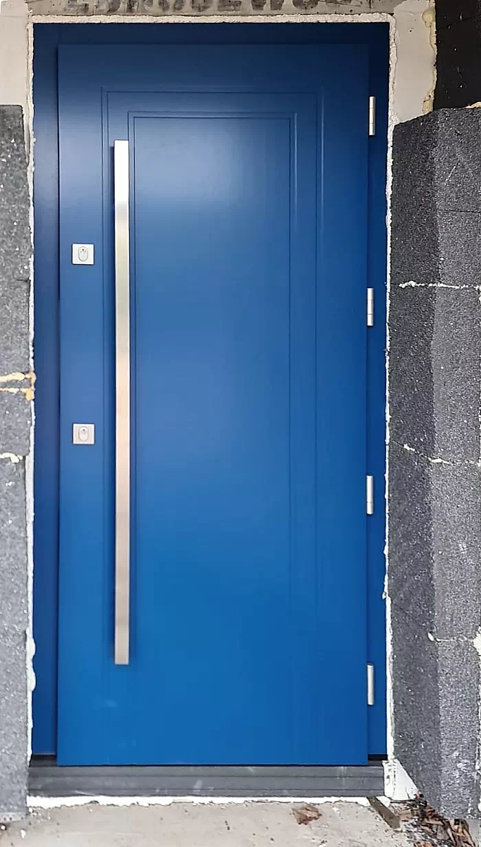 Widok elewacji domu z zamontowanymi drzwiami wzór 642,2 wymalowanymi w kolorze niebieskie.