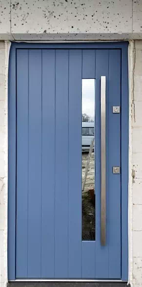 Widok elewacji domu z zamontowanymi drzwiami wzór 689,7s1 wymalowanymi w kolorze niebieskie.