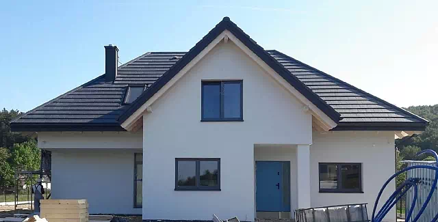 Widok elewacji domu z zamontowanymi drzwiami wzór 500C wymalowanymi w kolorze niebieskie.