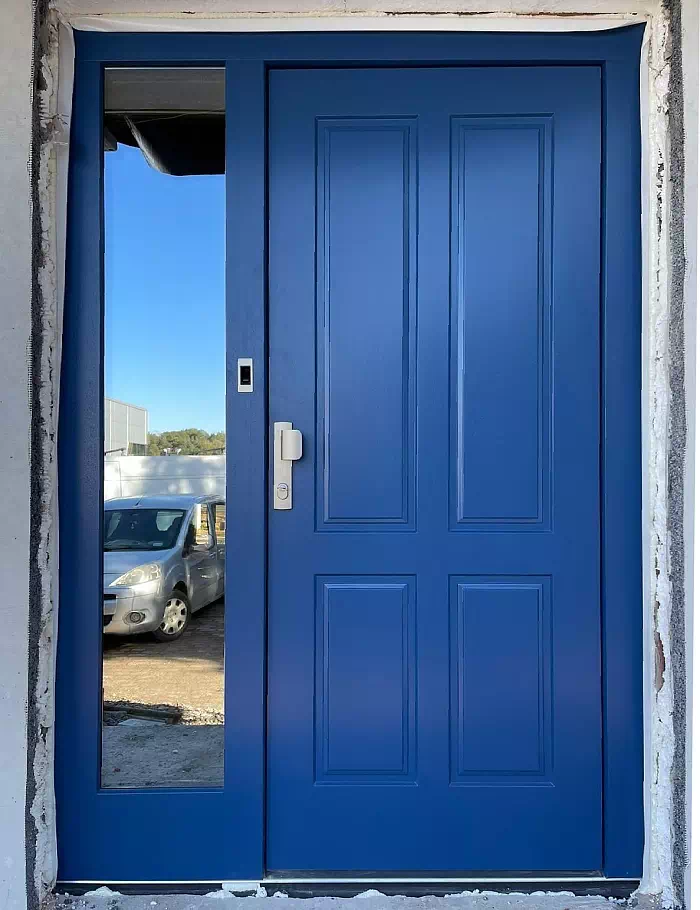 Widok elewacji domu z zamontowanymi drzwiami wzór 534,9 wymalowanymi w kolorze granatowe.