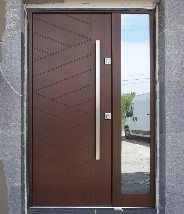 Widok elewacji domu z zamontowanymi drzwiami wzór 430,14 wymalowanymi w kolorze orzech.