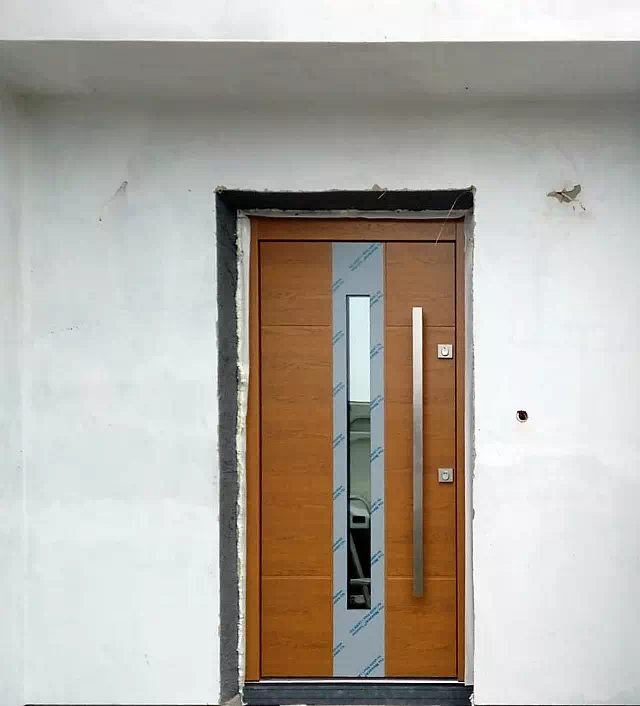 Widok elewacji domu z zamontowanymi drzwiami wzór 449,3 wymalowanymi w kolorze złoty dąb.