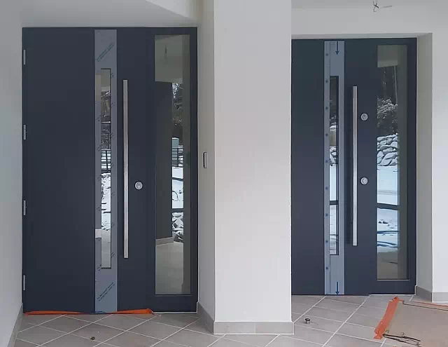 Widok elewacji domu z zamontowanymi drzwiami wzór 454,2 wymalowanymi w kolorze antracyt.