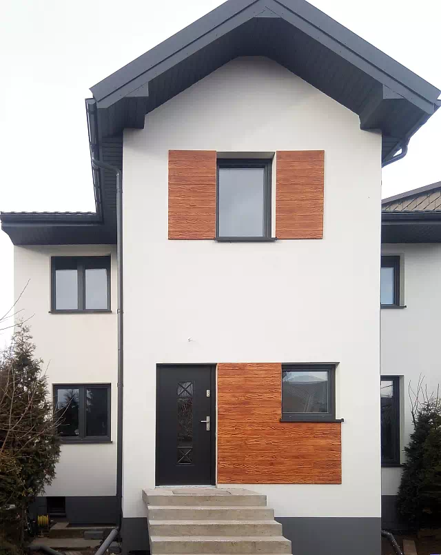 Widok elewacji domu z zamontowanymi drzwiami wzór 461,1 wymalowanymi w kolorze czarne.