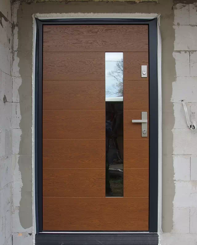 Widok elewacji domu z zamontowanymi drzwiami wzór 476,4 wymalowanymi w kolorze ciemny dąb.