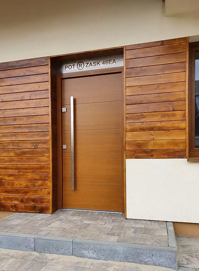 Widok elewacji domu z zamontowanymi drzwiami wzór 490,15 wymalowanymi w kolorze złoty dąb.