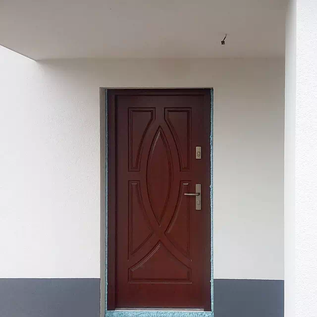 Widok elewacji domu z zamontowanymi drzwiami wzór 503,1 wymalowanymi w kolorze teak.