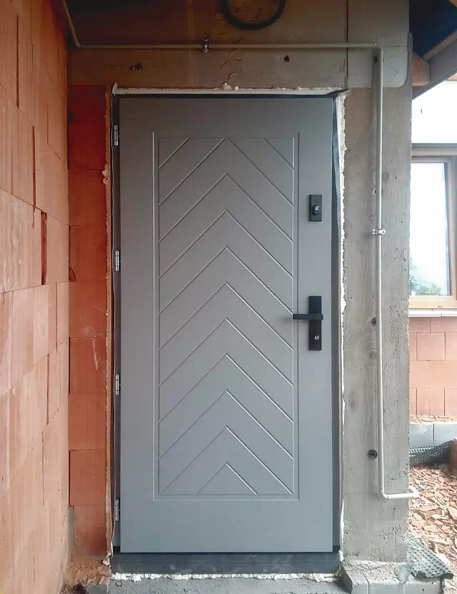 Widok elewacji domu z zamontowanymi drzwiami wzór 543,2B wymalowanymi w kolorze szare.