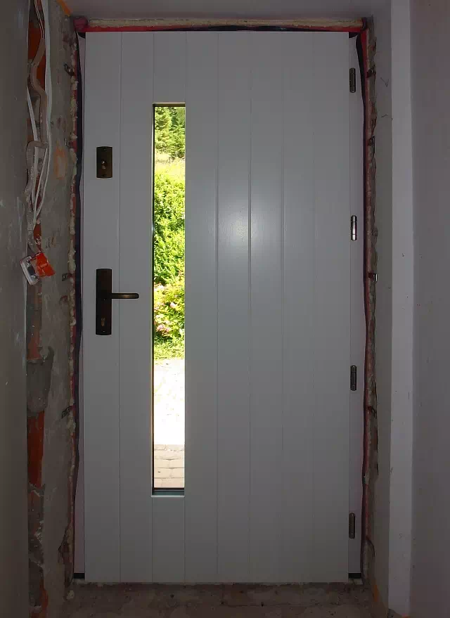 Widok elewacji domu z zamontowanymi drzwiami wzór 689,7s1 wymalowanymi w kolorze białe.