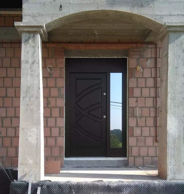 Widok elewacji domu z zamontowanymi drzwiami wzór 899 wymalowanymi w kolorze dąb bagienny.