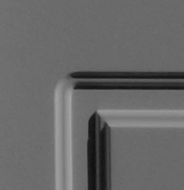 Widok na narożnik nowoczesnego przefrezowania stosowanego w kasetonach drewnianych drzwi zewnętrznych.