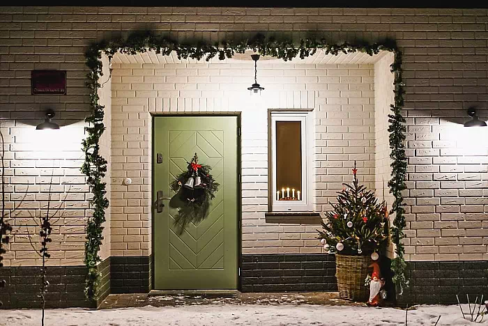 Widok elewacji domu z zamontowanymi drzwiami wzór 543,3 wymalowanymi w kolorze zielone.