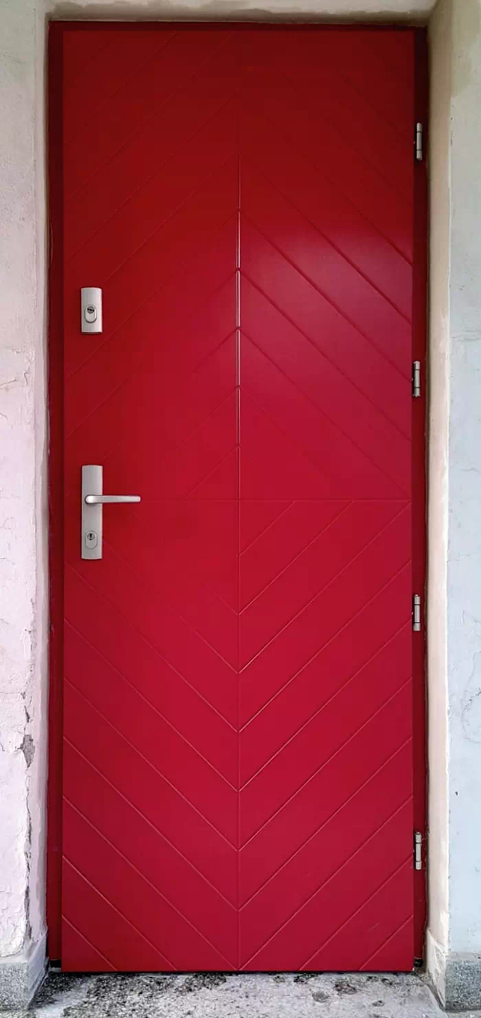 Widok elewacji domu z zamontowanymi drzwiami wzór 542,1 wymalowanymi w kolorze czerwone.