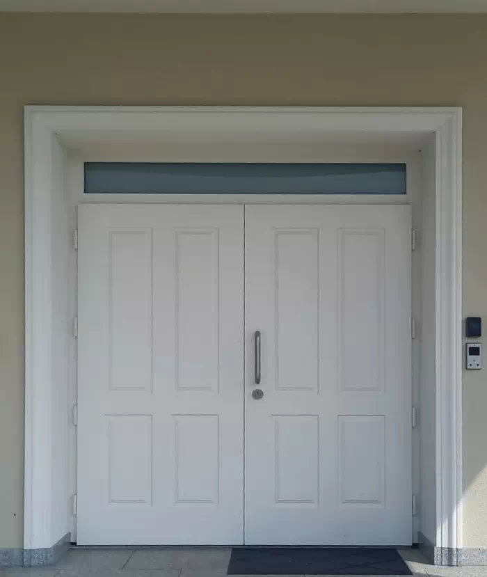 Widok elewacji domu z zamontowanymi drzwiami wzór 534,9 wymalowanymi w kolorze białe.