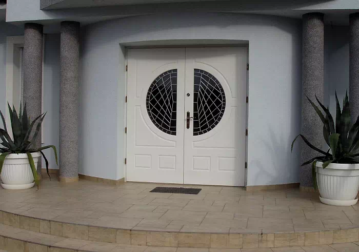 Widok elewacji domu z zamontowanymi drzwiami wzór 896,1 wymalowanymi w kolorze białe.