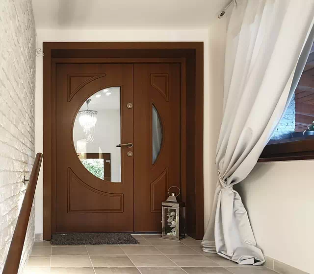 Widok elewacji domu z zamontowanymi drzwiami wzór 902,1 wymalowanymi w kolorze teak.