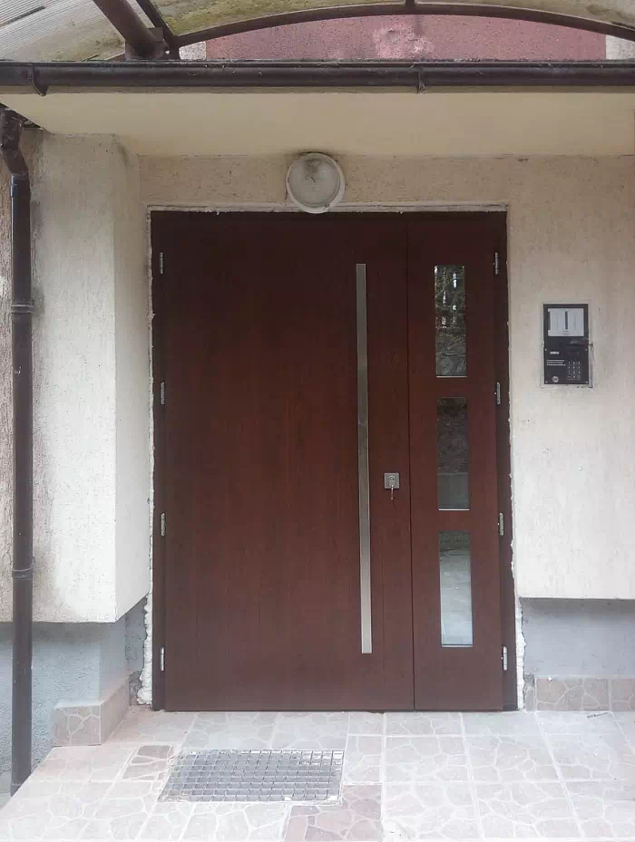 Widok elewacji domu z zamontowanymi drzwiami wzór 989,1 wymalowanymi w kolorze orzech.