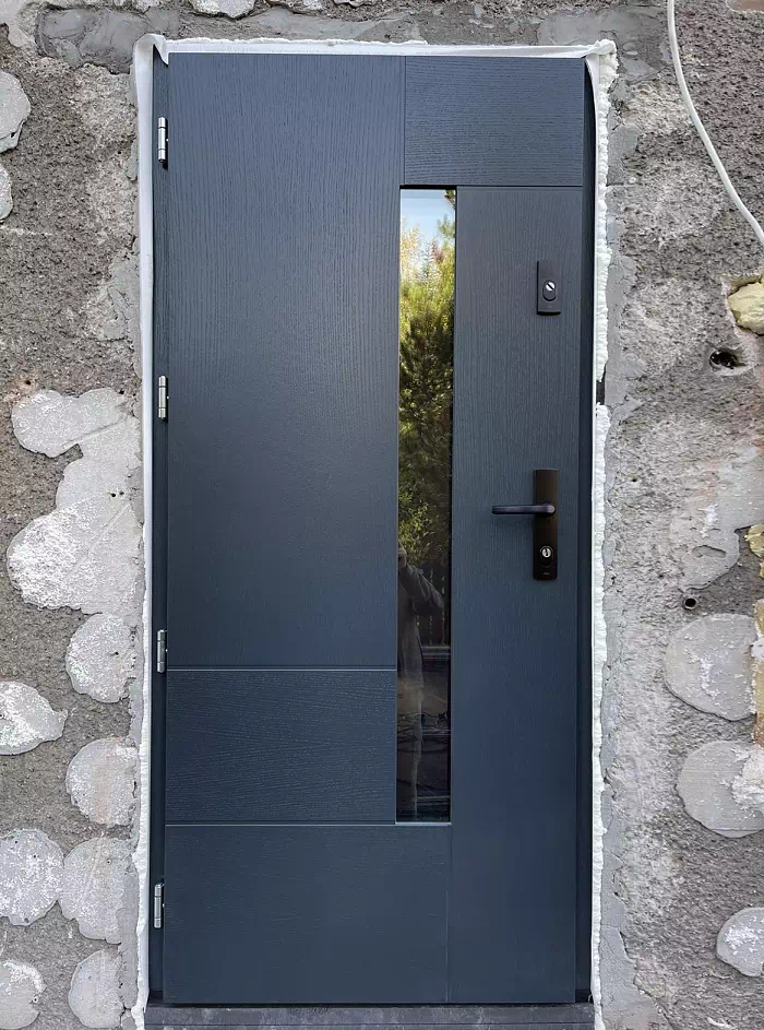 Widok elewacji domu z zamontowanymi drzwiami wzór 413,11 wymalowanymi w kolorze dębowe antracytowe.