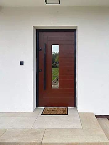 Widok elewacji domu z zamontowanymi drzwiami wzór 414,20 wymalowanymi w kolorze teak.