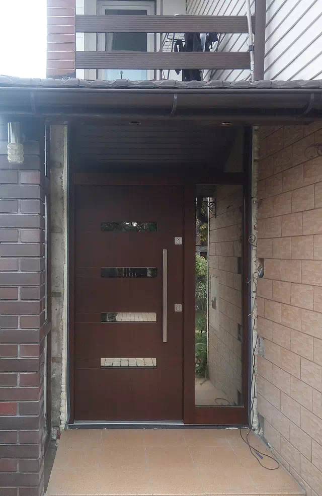 Widok elewacji domu z zamontowanymi drzwiami wzór 422,13 wymalowanymi w kolorze orzech.