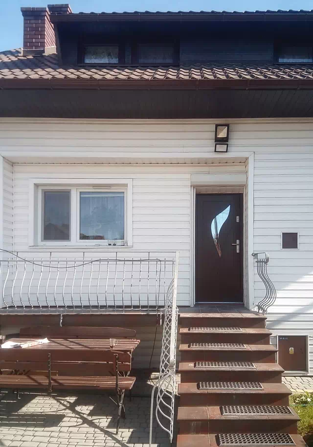 Widok elewacji domu z zamontowanymi drzwiami wzór 458,4 wymalowanymi w kolorze orzech.