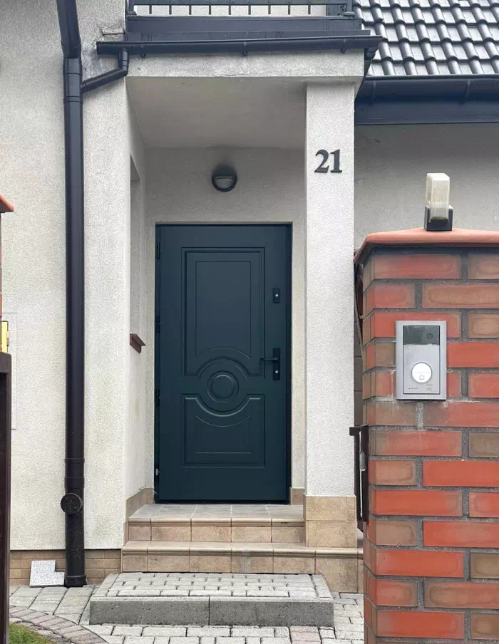 Widok elewacji domu z zamontowanymi drzwiami wzór 504,4 wymalowanymi w kolorze czarne.