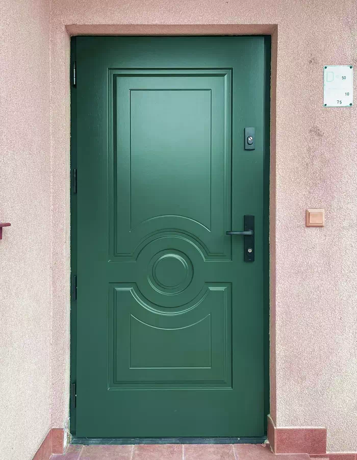 Widok elewacji domu z zamontowanymi drzwiami wzór 504,4 wymalowanymi w kolorze zielone.