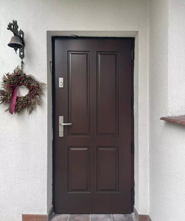 Widok elewacji domu z zamontowanymi drzwiami wzór 534,9 wymalowanymi w kolorze orzech.