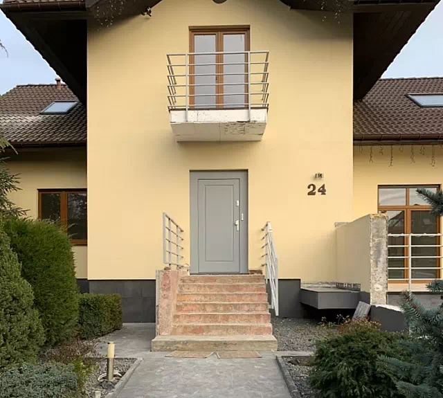 Widok elewacji domu z zamontowanymi drzwiami wzór 535,5 wymalowanymi w kolorze szare.