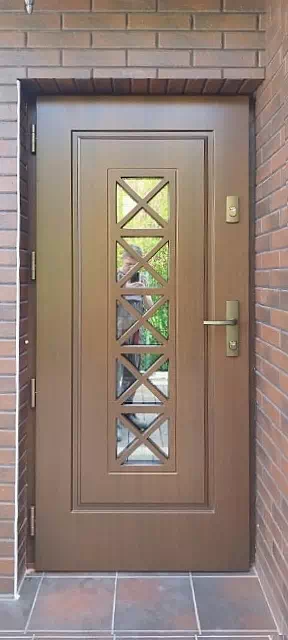 Widok elewacji domu z zamontowanymi drzwiami wzór 546,1 wymalowanymi w kolorze ciemny dąb.