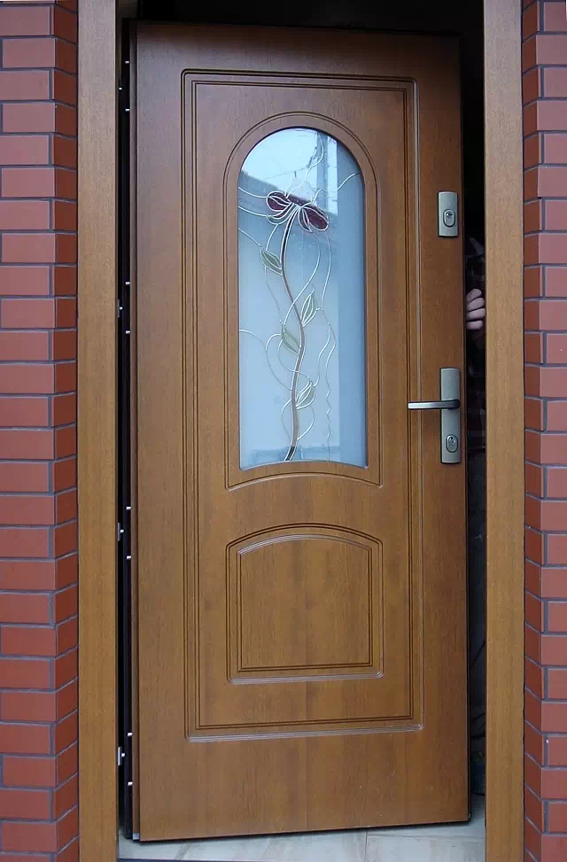 Widok elewacji domu z zamontowanymi drzwiami wzór 576s1+ds1 wymalowanymi w kolorze złoty dąb.