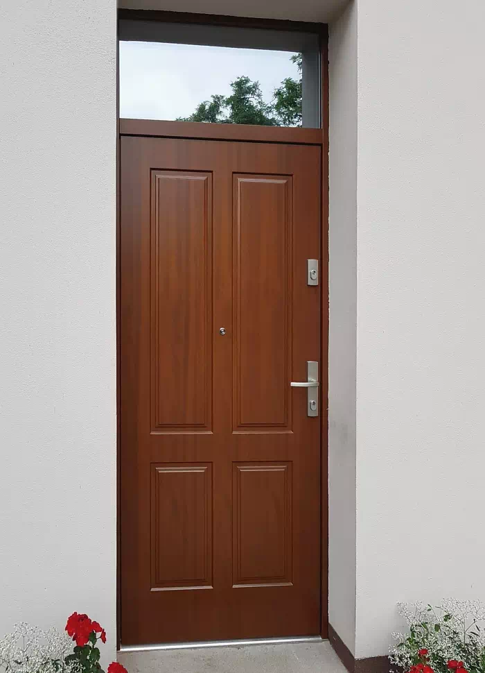 Widok elewacji domu z zamontowanymi drzwiami wzór 534,9 wymalowanymi w kolorze orzech.