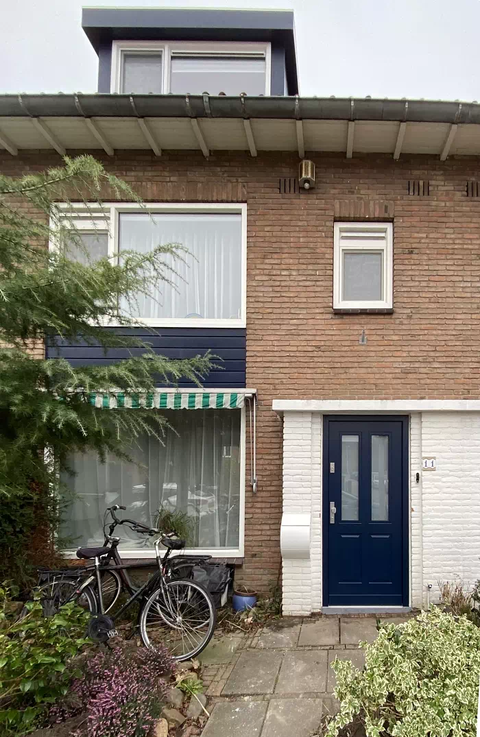 Widok elewacji domu z zamontowanymi drzwiami wzór 534,9 wymalowanymi w kolorze granatowe.