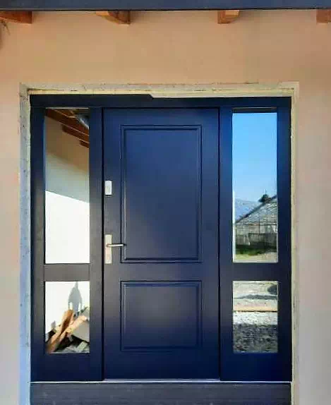 Widok elewacji domu z zamontowanymi drzwiami wzór 535,6 wymalowanymi w kolorze granatowe.