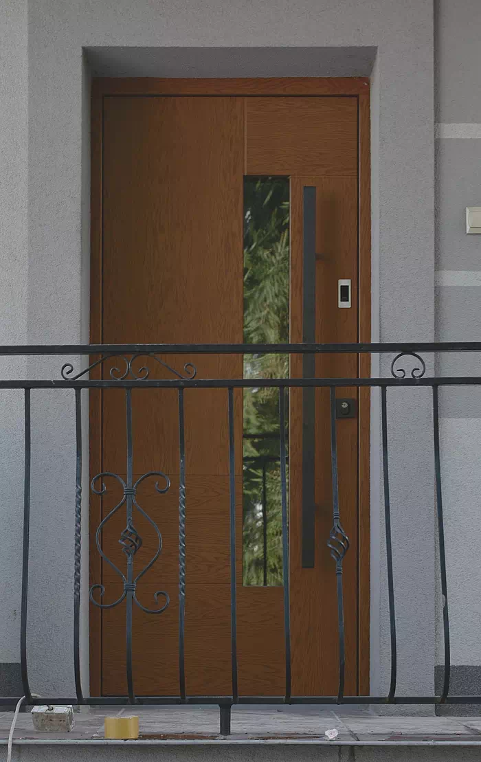 Widok elewacji domu z zamontowanymi drzwiami wzór 413,11c wymalowanymi w kolorze ciemny dąb.