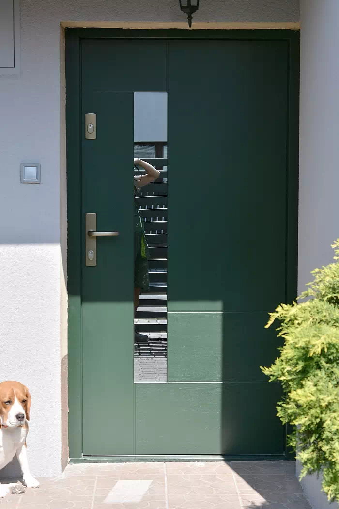 Widok elewacji domu z zamontowanymi drzwiami wzór 413,11c wymalowanymi w kolorze zielone.