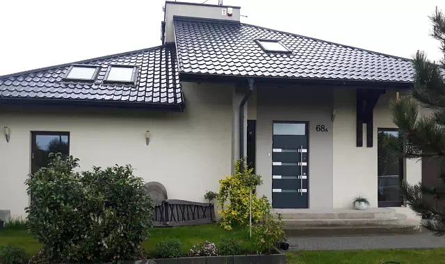 Widok elewacji domu z zamontowanymi drzwiami wzór 422,1 wymalowanymi w kolorze RAL 7016.