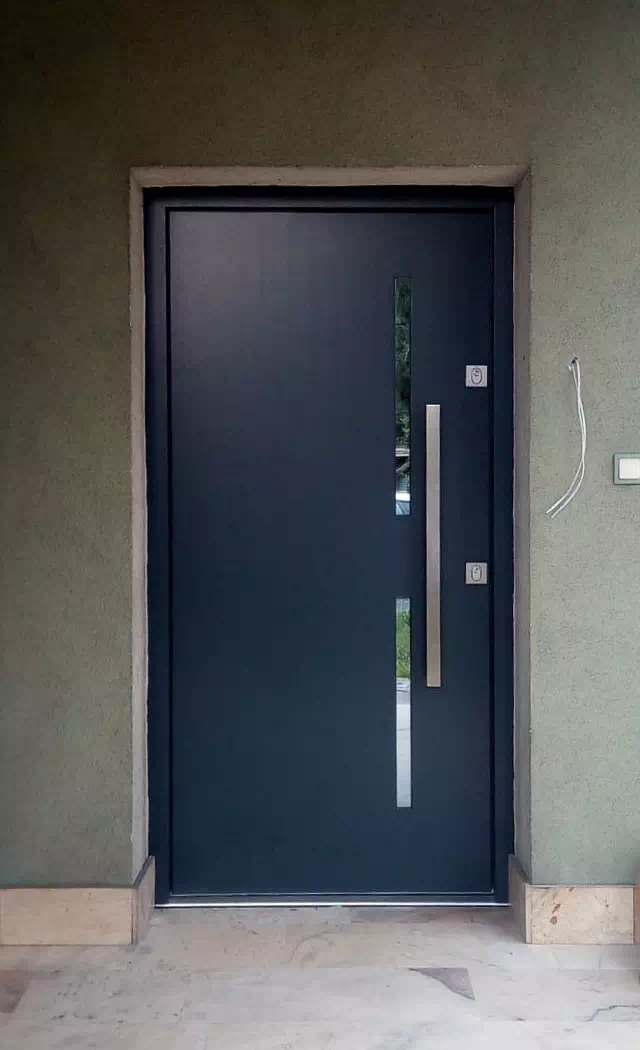 Widok elewacji domu z zamontowanymi drzwiami wzór 453,11 wymalowanymi w kolorze antracyt.