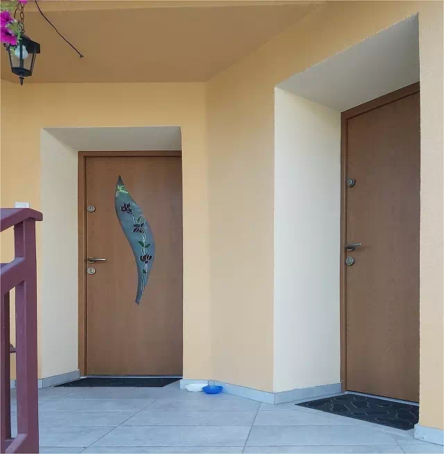 Widok elewacji domu z zamontowanymi drzwiami wzór 458,6+ds56 wymalowanymi w kolorze jasny dąb.