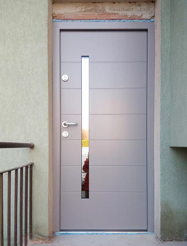 Widok elewacji domu z zamontowanymi drzwiami wzór 476,3 wymalowanymi w kolorze szare.