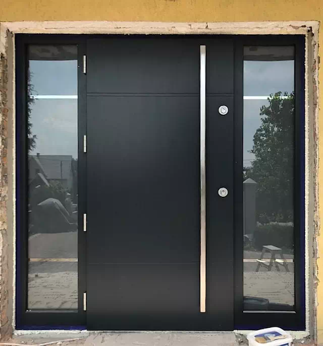 Widok elewacji domu z zamontowanymi drzwiami wzór 490,11 wymalowanymi w kolorze antracyt.